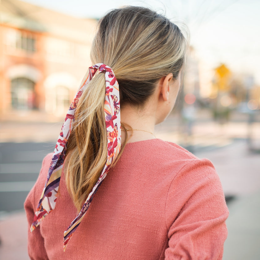 woman wearing butterfly floral print hair scarf in salmon blouse