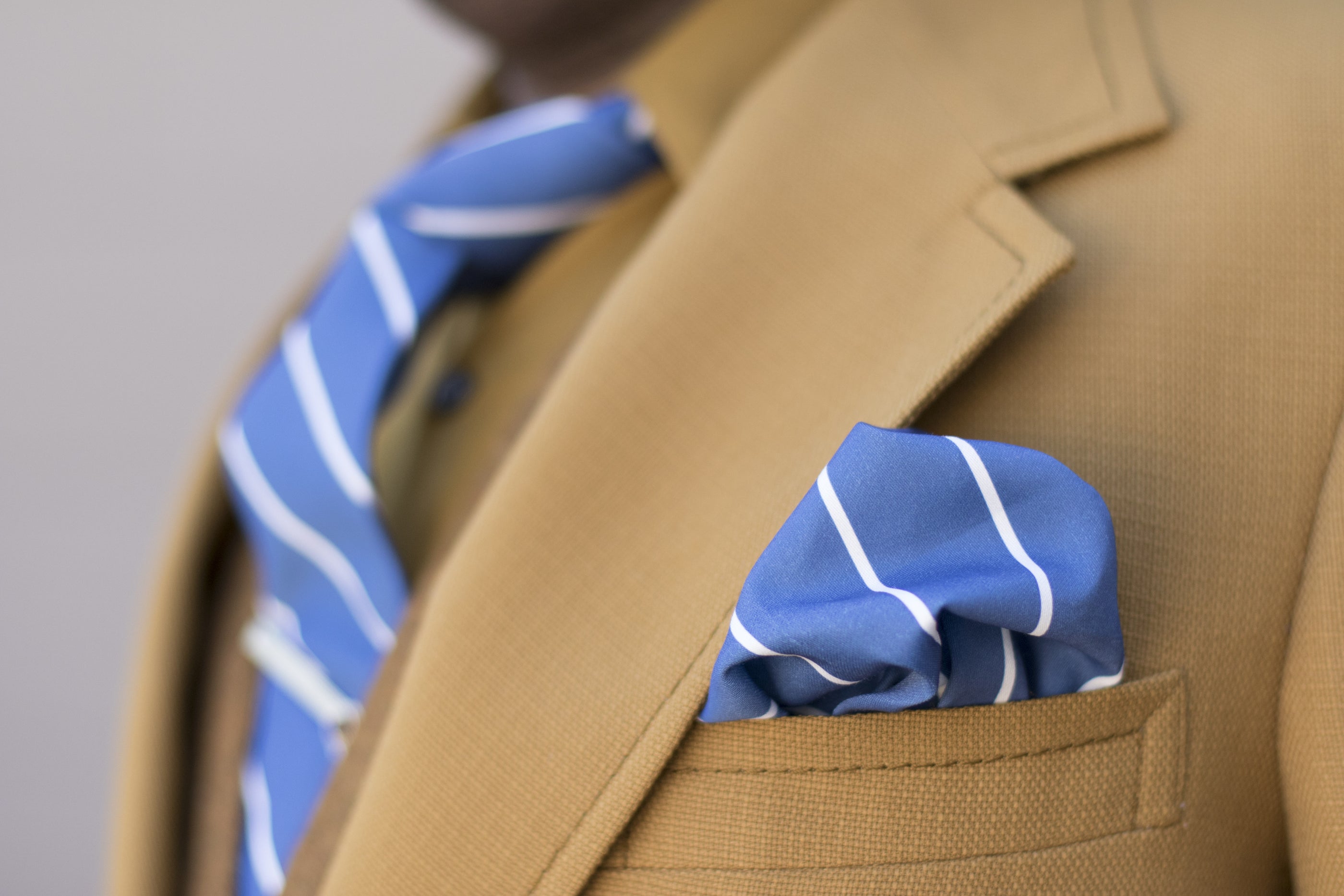blue striped pocket square in pocket of brown suit