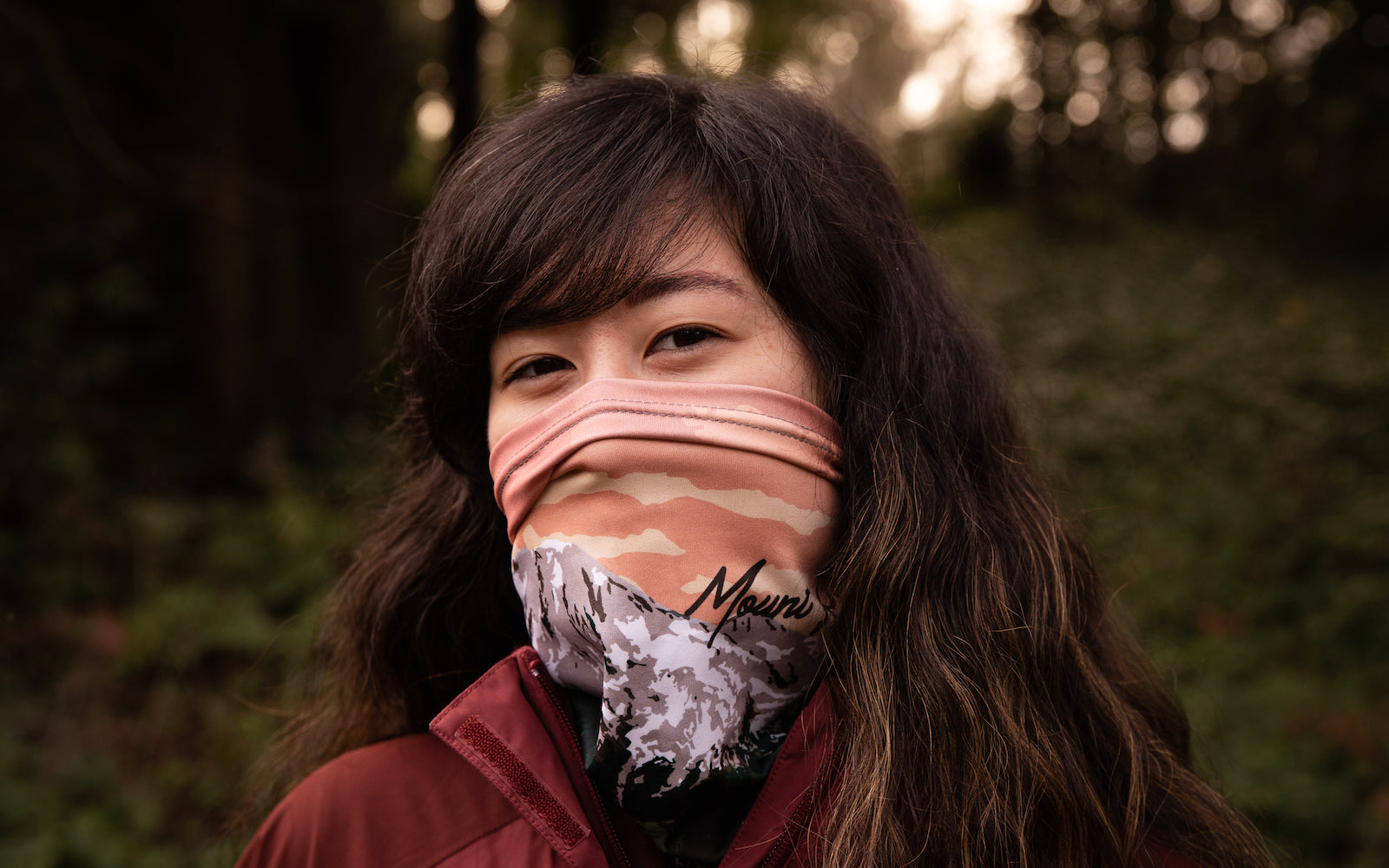 woman in the woods wearing a neck gaiter featuring mount rainier design